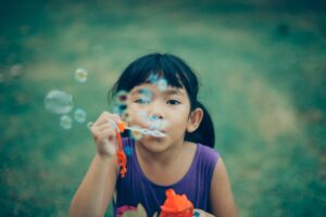 young child blowing bubbles outdoors