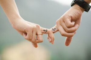 a couple holding hands with matching "anchor" finger tattoos