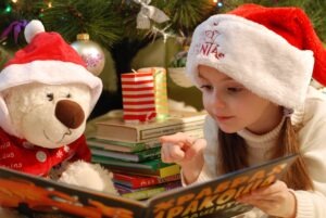 child reading a book to a stuffed animal during Christmas