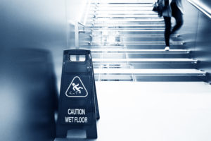 black & white photo of slip & fall wet floor sign and stairs