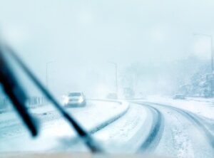 The view of a snow-covered road from the windshield of car.