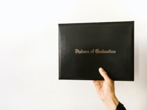 The hand of a man holding out his graduation diploma for the camera.