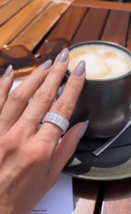 A woman wearing a three-row asscher cut diamond platinum eternity band on her left hand is enjoying her coffee.