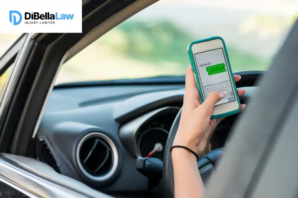 Teenage girl sits in a car driving with one hand on the steering wheel and the other hand on a mobile phone