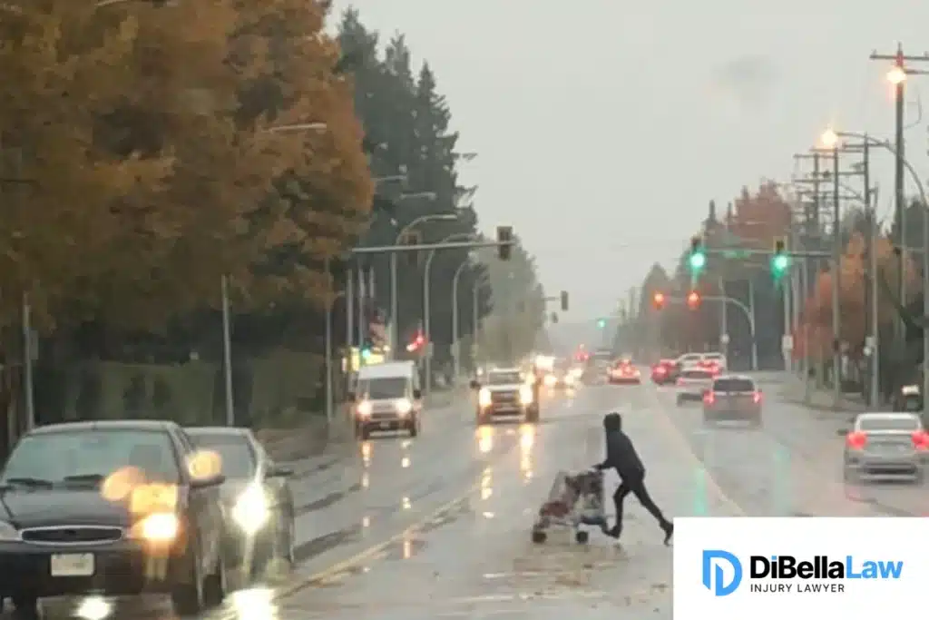 A jaywalker pushing a trolley while attempting to cross the road during the rainy season.