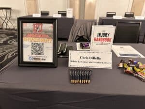 DiBella's table with the Injury Handbook and other swag set up at the New England Law School event