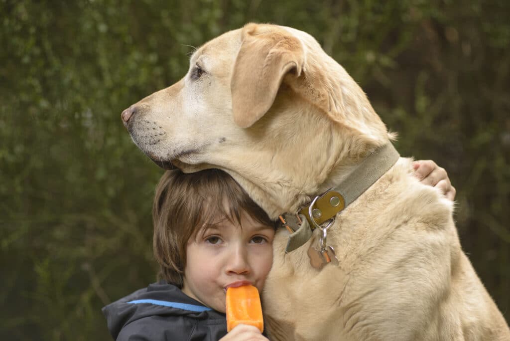 child-hugging-dog-while-eating-popsicle
